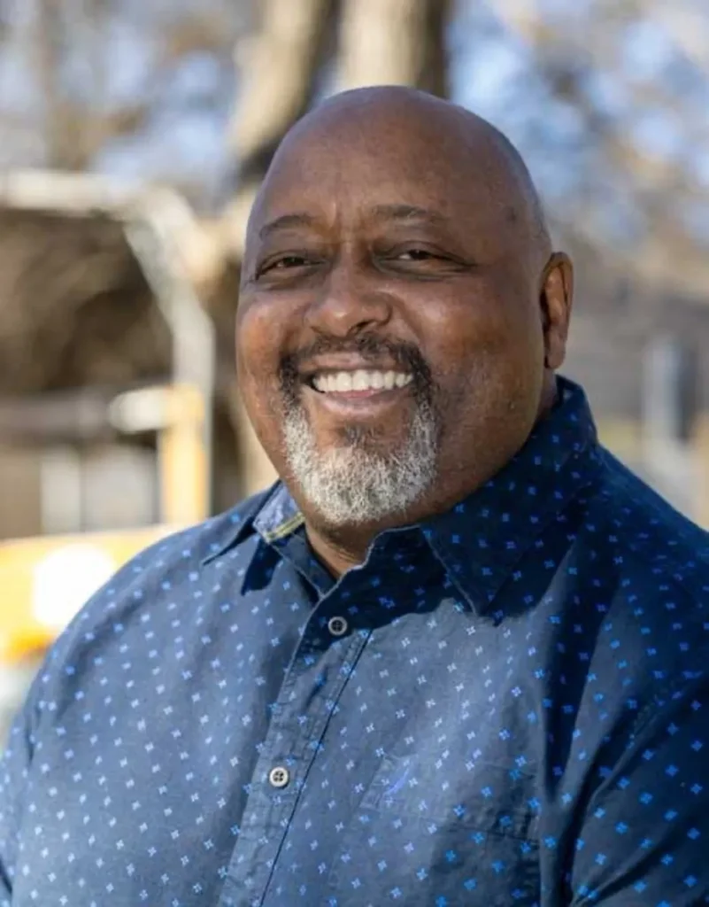 Smiling man in a blue patterned shirt.