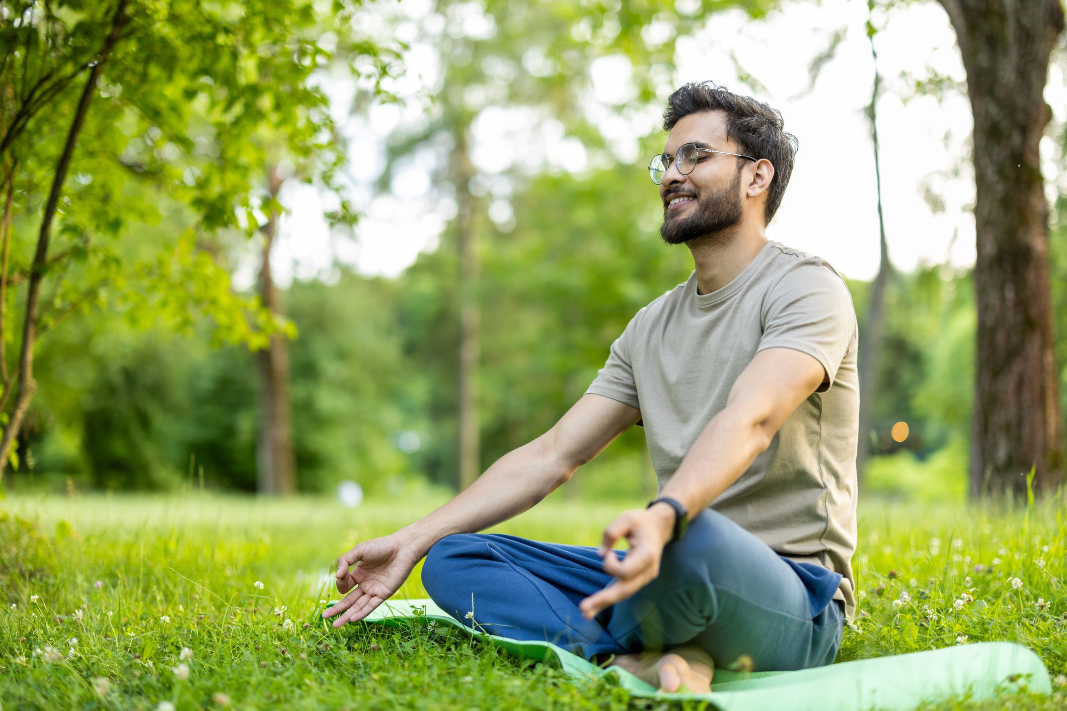 A man meditating outdoors in a peaceful park.