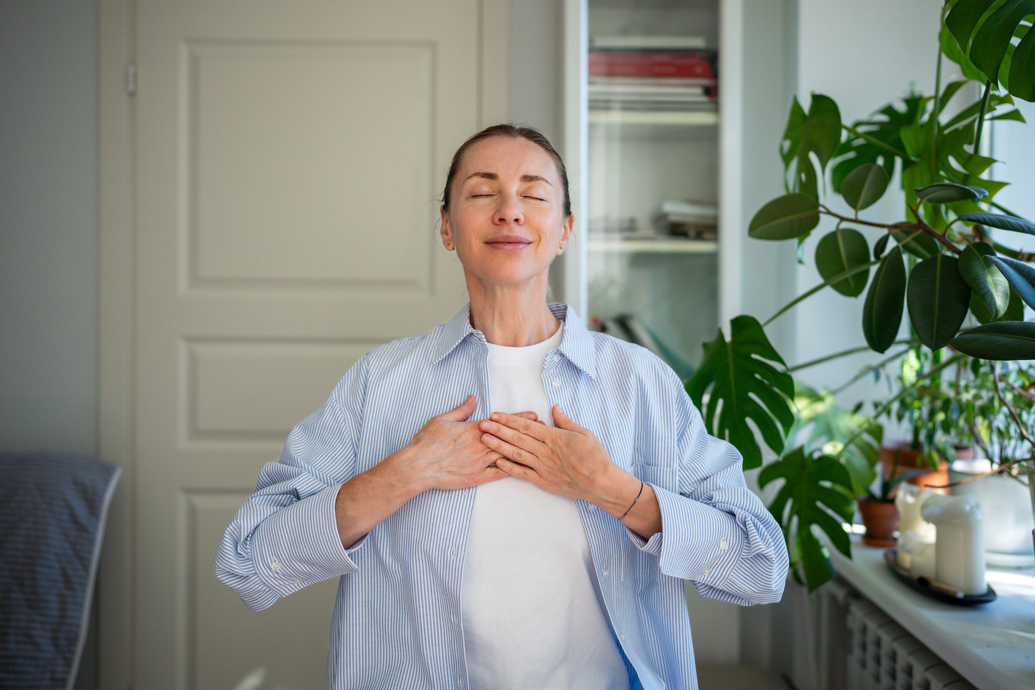 Woman practicing mindfulness with closed eyes and hands on chest.