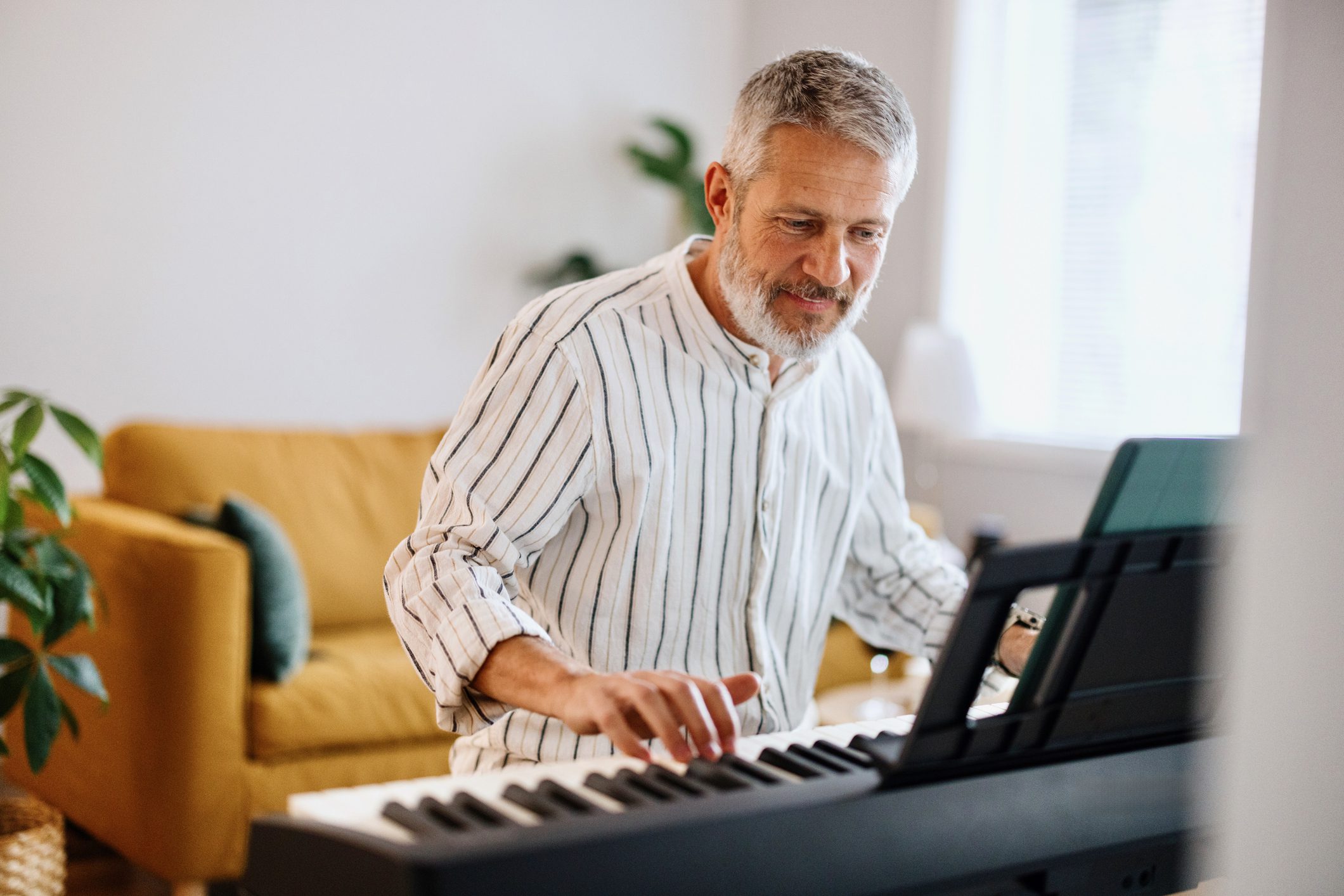 Older man playing a keyboard piano indoors.