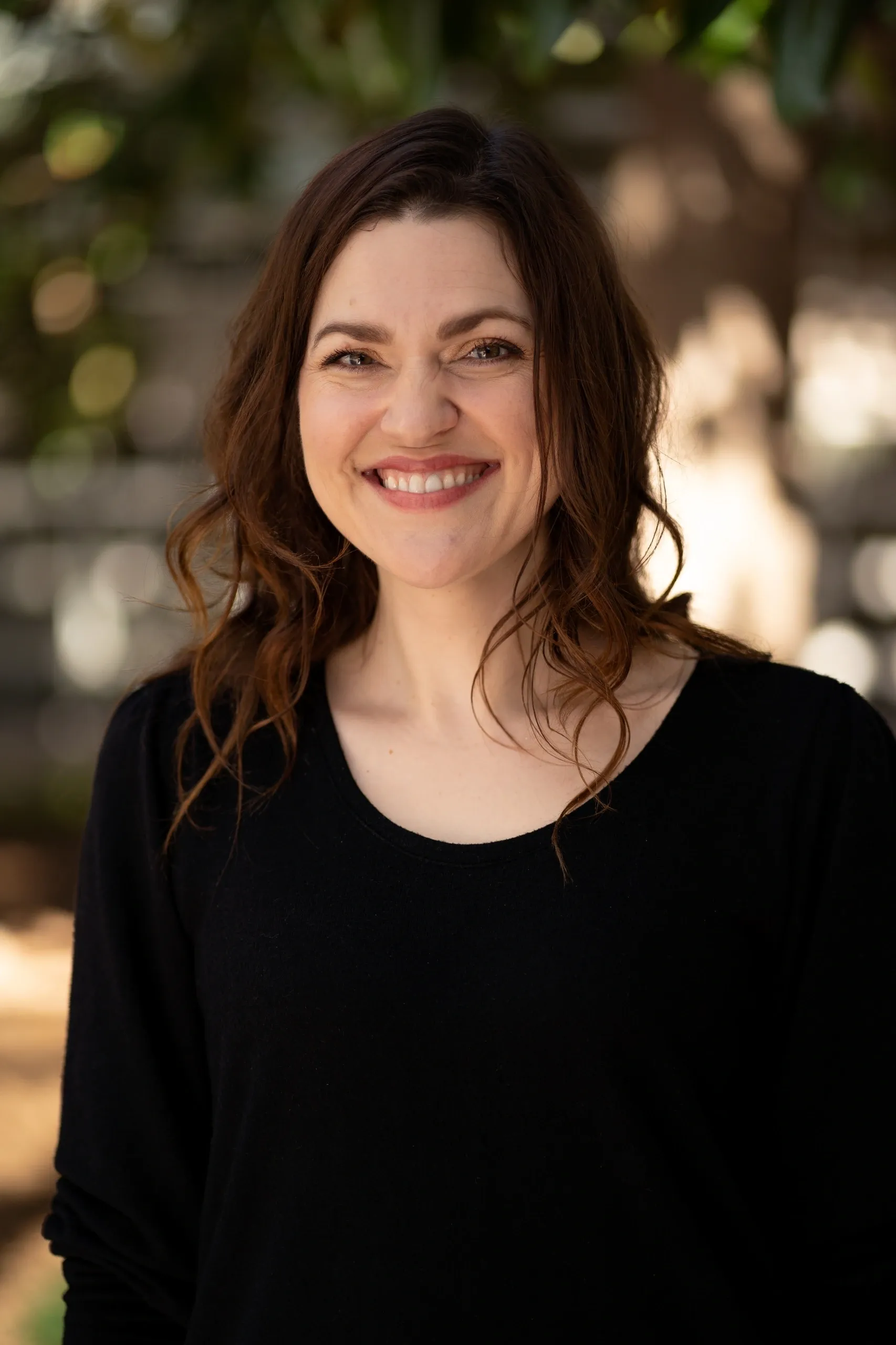 Smiling woman in a black top outdoors.