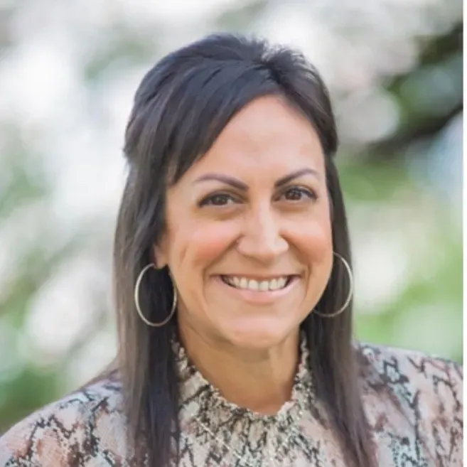 Smiling woman with hoop earrings outdoors.