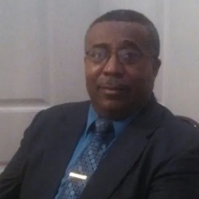 Man in suit with glasses, sitting indoors.