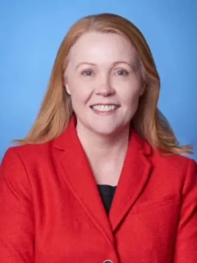 Smiling woman in red blazer, blue background.