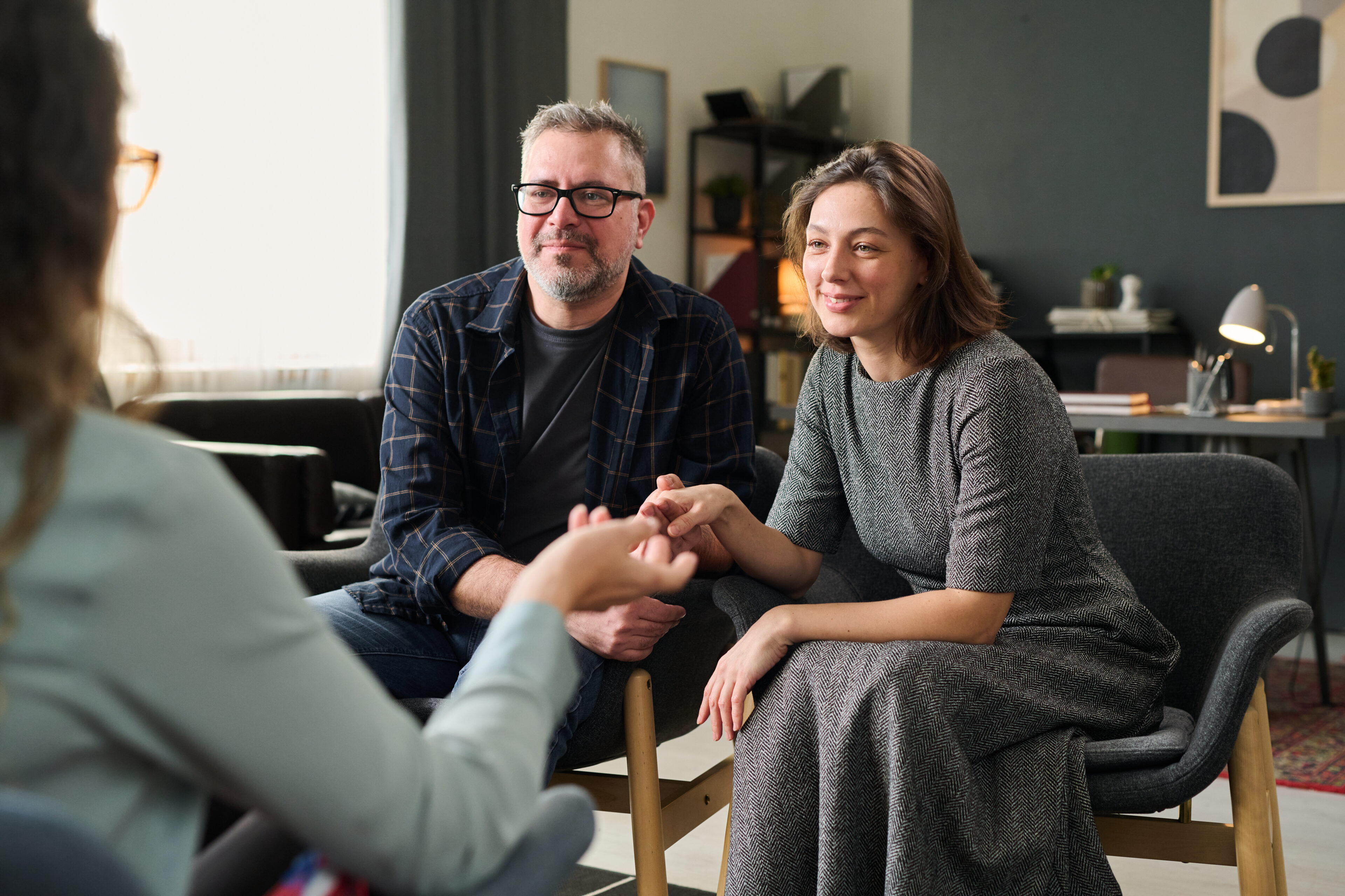 Couple holding hands with a therapist during a counseling session.