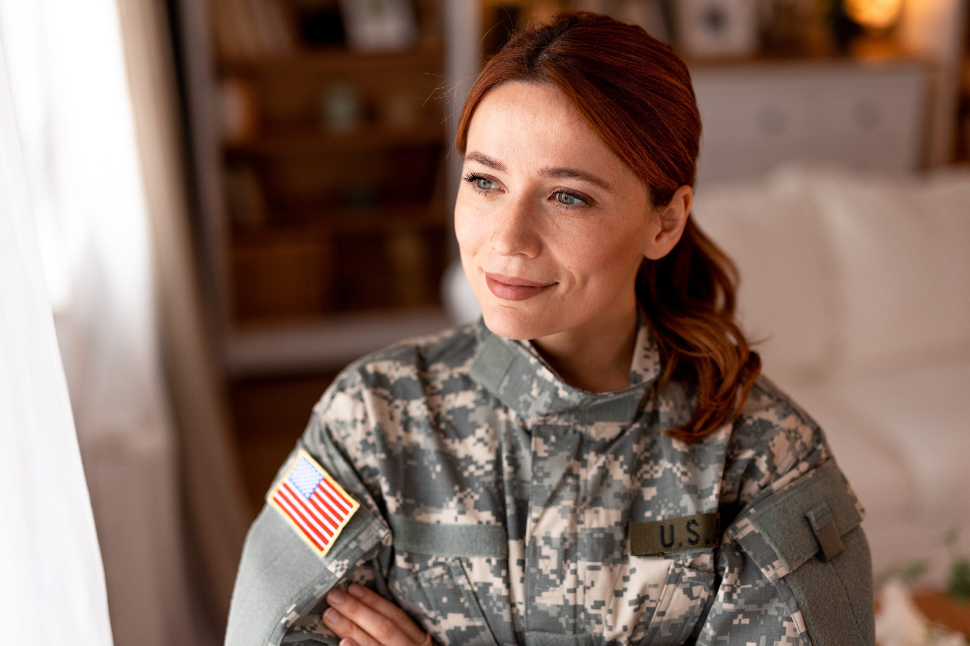 Confident female soldier in camouflage uniform with an American flag patch.