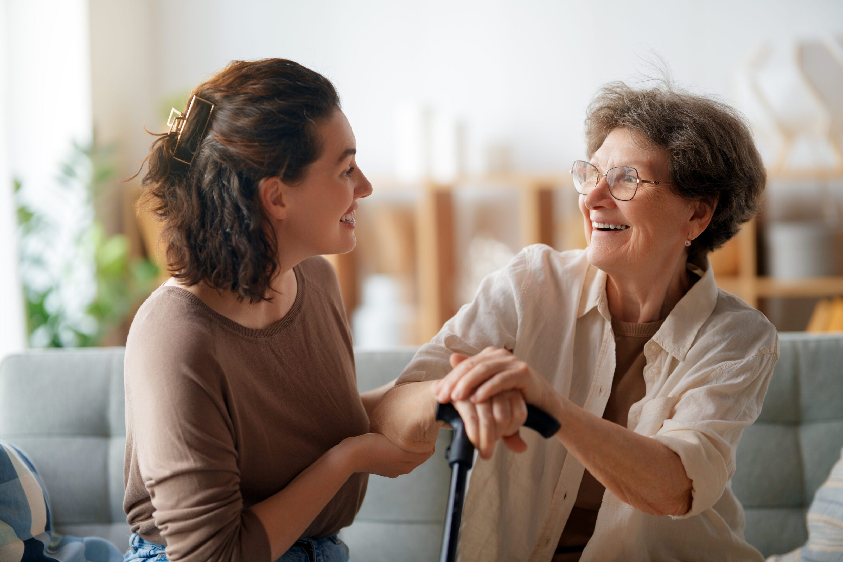 Young woman holding hands with elderly woman, sharing a warm moment.