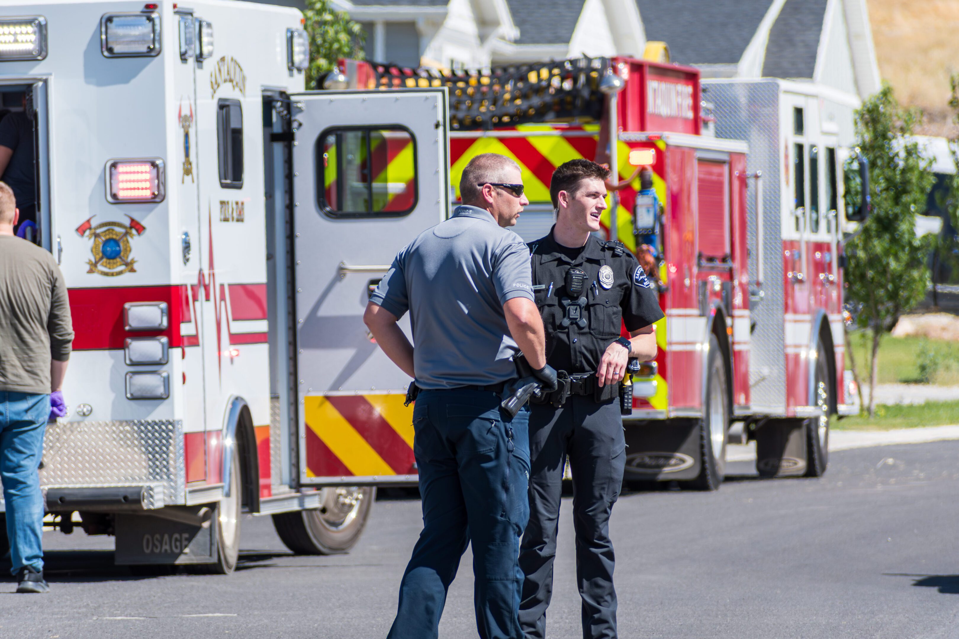 Two emergency responders standing and talking near ambulances.